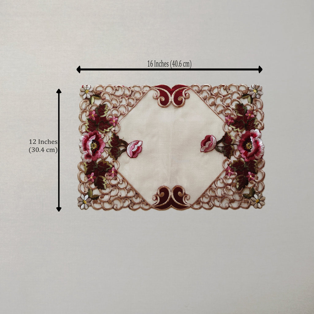 An embroidered lace table mat with a cream center and pink floral motifs, shown with black dimension lines indicating 16 inches by 12 inches.