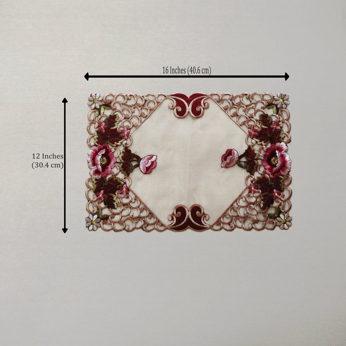 An embroidered lace table mat with a cream center and pink floral motifs, shown with black dimension lines indicating 16 inches by 12 inches.