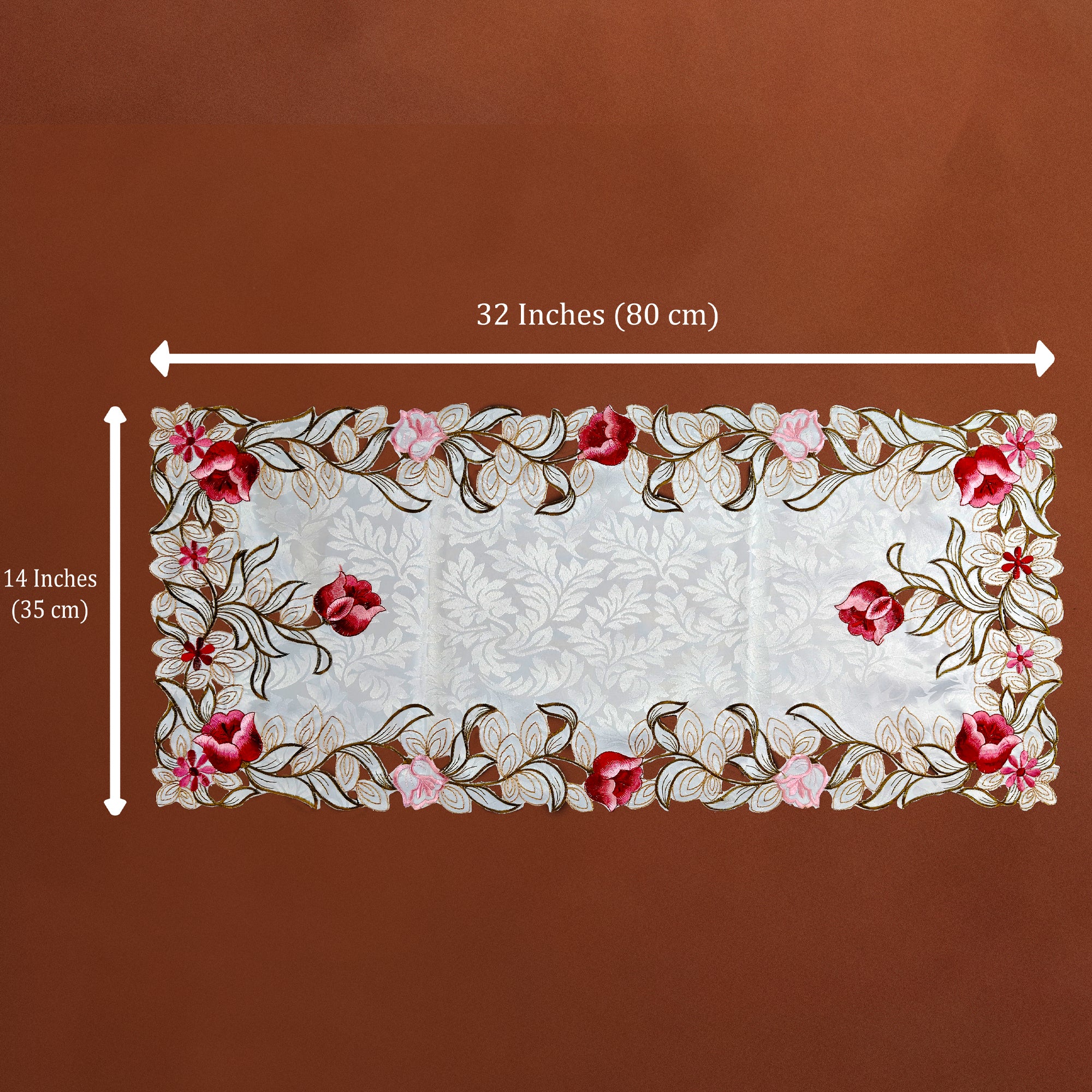 A rectangular embroidered table runner shown on a brown background with white dimension arrows and text indicating 32 inches by 14 inches (80 cm by 35 cm). The runner has a white center with floral embroidery around the border in red, pink, and brown tones.