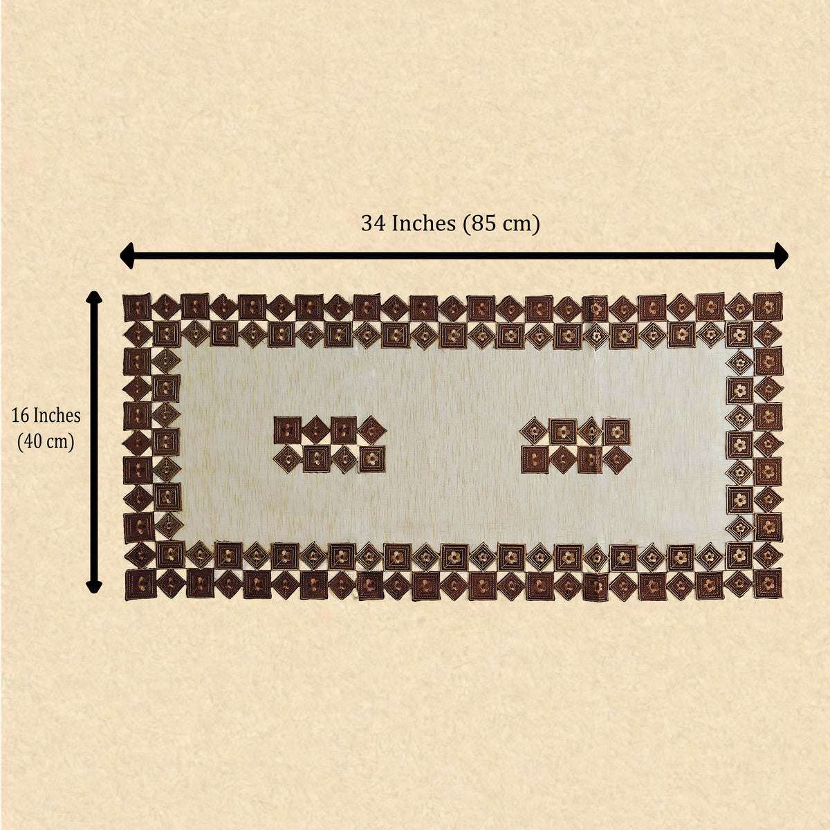 A rectangular patchwork table runner made of many small brown and cream fabric squares, shown on a beige background with measurement arrows labeling it 34 inches by 16 inches.