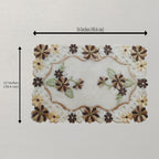 A rectangular embroidered patch shown on a light neutral background, with black dimension arrows indicating 16 inches by 12 inches. The design features cream lace-like border, brown and beige floral motifs, and green leaf accents on a white center.