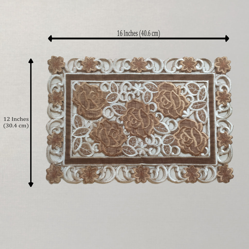 A rectangular placemat with ornate lace-like detailing and raised rose motifs, shown on a light neutral background with dimension arrows indicating 16 inches by 12 inches.