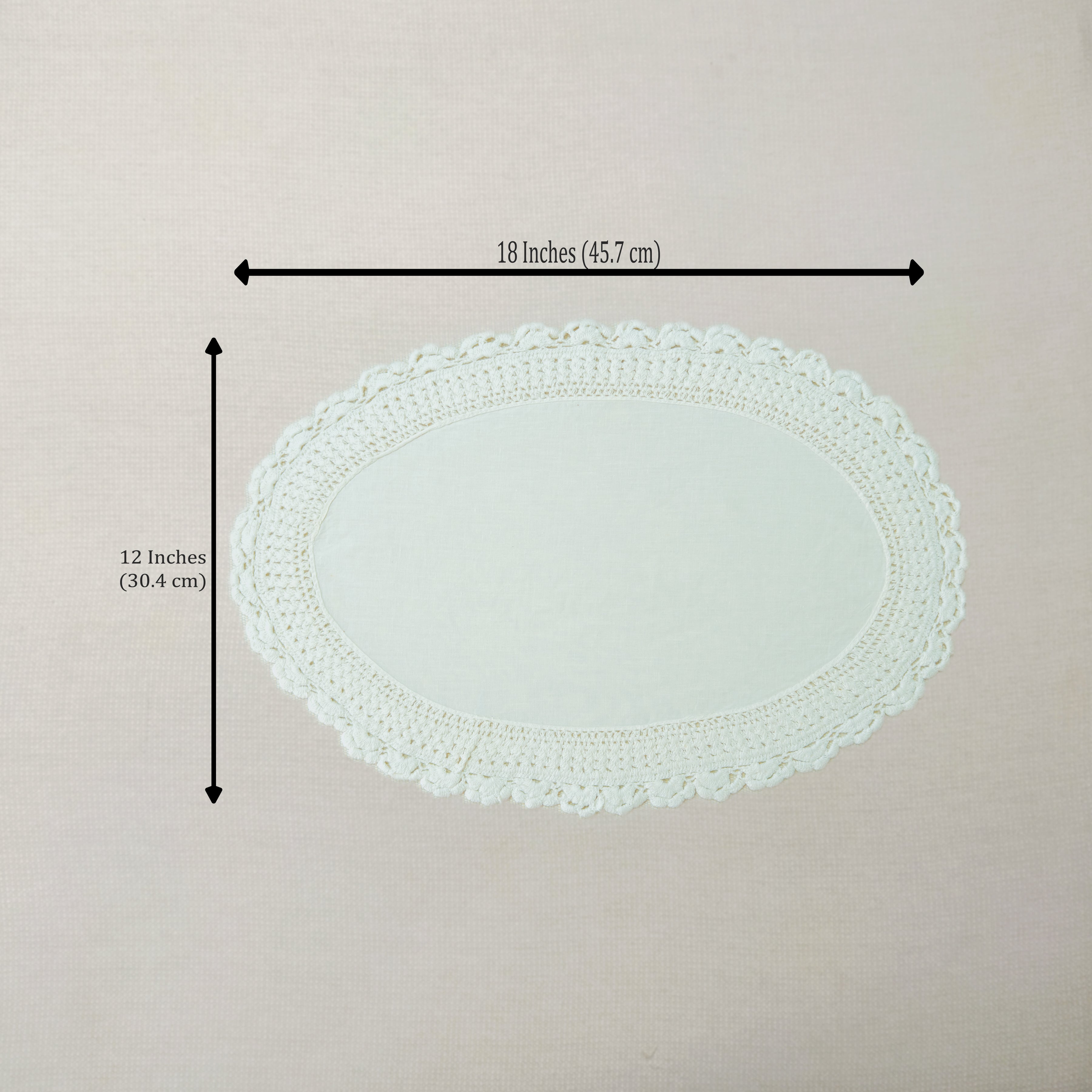 An oval white crocheted lace doily with dimension arrows and text indicating a width of 18 inches (45.7 cm) and a height of 12 inches (30.
