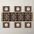 A set of table linens including a long runner and six placemats, featuring ornate gold and white baroque-style damask patterns.