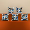 An orange upholstered sofa with five decorative throw pillows featuring a blue, brown, and white abstract pattern, set against a beige wall and light wood floor.