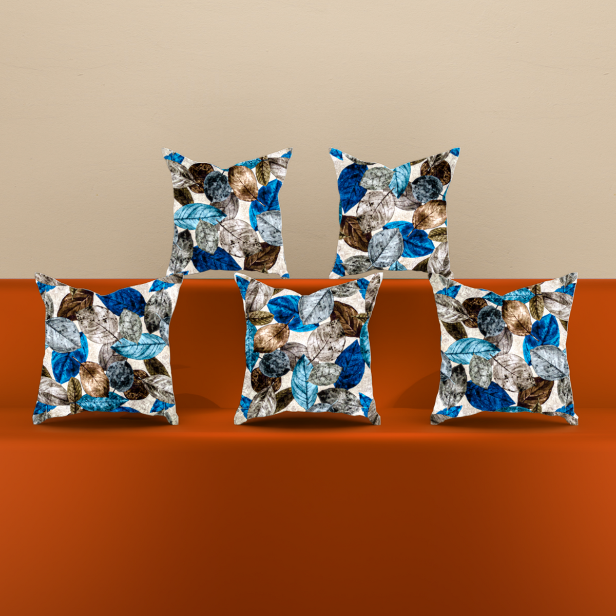 An orange upholstered sofa with five decorative throw pillows featuring a blue, brown, and white abstract pattern, set against a beige wall and light wood floor.