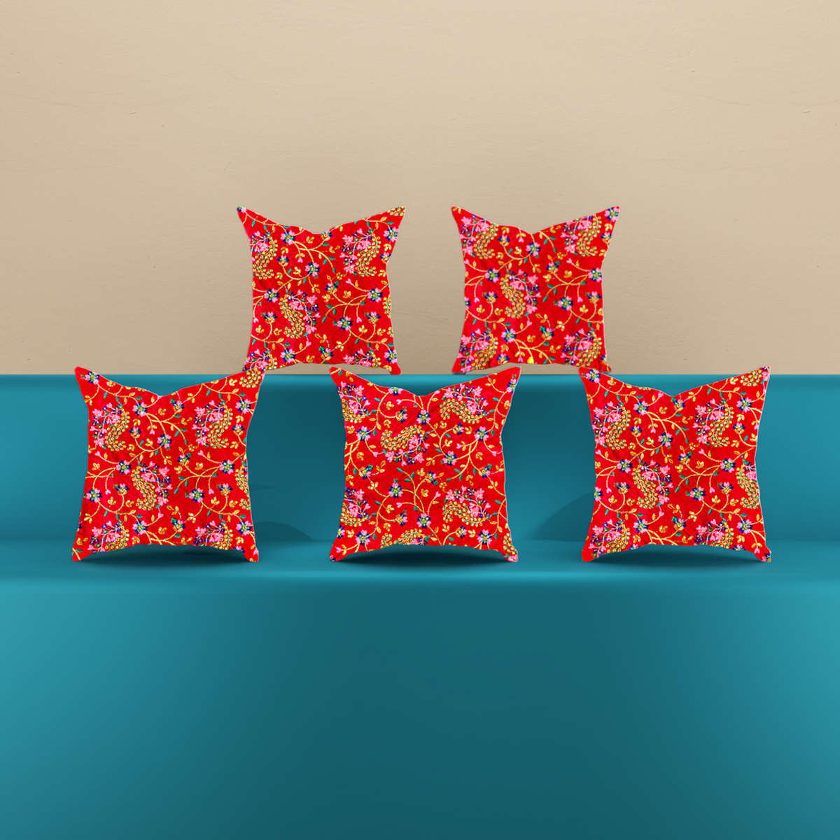 A turquoise blue sofa with five decorative throw pillows featuring a red floral pattern, set against a plain beige wall and light wood floor.